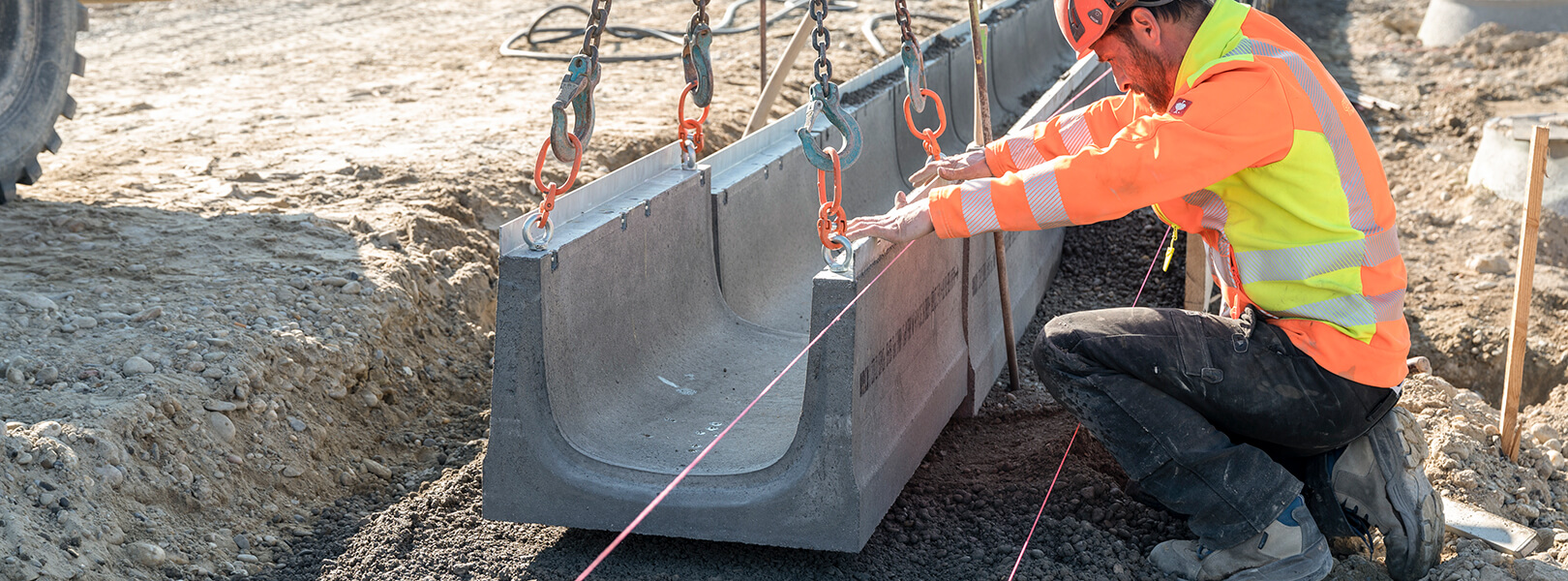 Mitarbeitender bei der exakten Versetzung von Entwässerungsrinnen aus Beton
